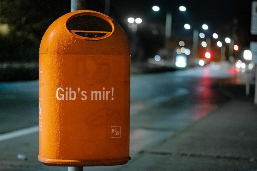 orange-metal-trash-bin-by-roadside-at-nighttime-qsv-schks-o